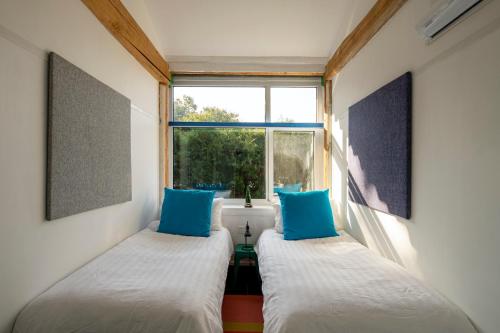 two beds in a small room with a window at Brickyard Retreat at Mutianyu Great Wall Adjoin to Mutianyu Great Wall - Room with the View of Great Wall - Chinese massage experience - Vehicle Shuttle Service - International Catering - SPA& Nail Beauty Facilities in Huairou