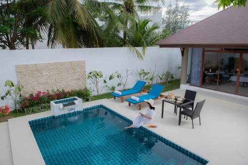 a child jumping into a swimming pool at Dhevan Dara Resort & Spa Hua Hin - Pool Villa in Hua Hin
