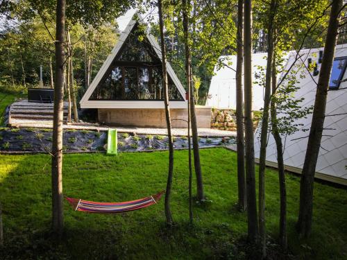 a hammock in the grass in front of a house at Trzy Owce - nowoczesne domki w górach in Białka Tatrzanska