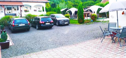 three cars parked in a parking lot next to a house at Harmony Vendégház Egerszalók in Egerszalók