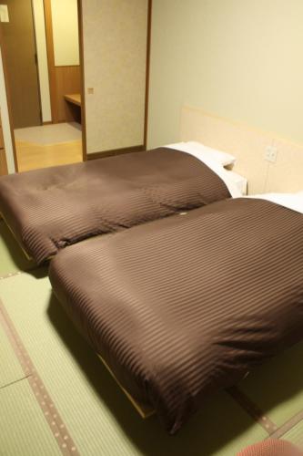 two beds sitting next to each other in a room at Hotel Mahoroba in Noboribetsu