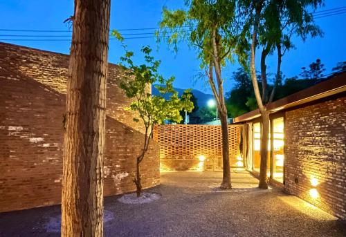 a brick wall with trees in front of a building at Brickyard Retreat at Mutianyu Great Wall Adjoin to Mutianyu Great Wall - Room with the View of Great Wall - Chinese massage experience - Vehicle Shuttle Service - International Catering - SPA& Nail Beauty Facilities in Huairou