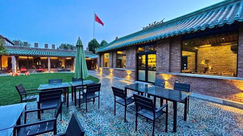 a patio with tables and chairs in front of a building at Brickyard Retreat at Mutianyu Great Wall Adjoin to Mutianyu Great Wall - Room with the View of Great Wall - Chinese massage experience - Vehicle Shuttle Service - International Catering - SPA& Nail Beauty Facilities in Huairou