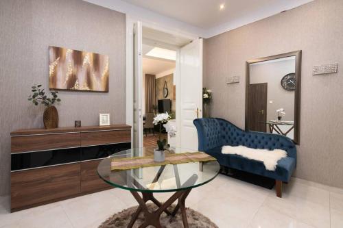 a living room with a blue chair and a glass table at Contemporary Hidden Gem Art-Deco Residence in Budapest