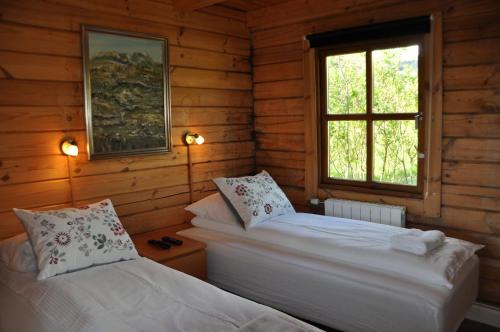2 camas en una cabaña de madera con ventana en North Star Cottage, en Eyvindarhólar