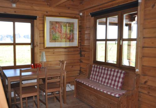 una sala da pranzo con un tavolo, una panca e finestre di North Star Cottage a Eyvindarhólar