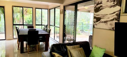 a dining room with a table and a couch at Eatons Retreat in Eatons Hill