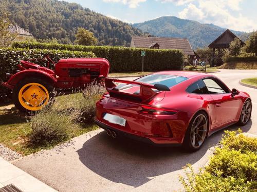 a red car parked in a driveway with a tractor at Na Vasi restavracija in prenočišča in Škofja Loka