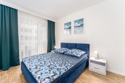 Un dormitorio con una cama azul y una ventana en Lily, en Kołobrzeg