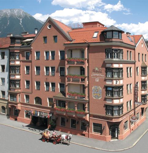 a large brick building with people sitting on a cart in front at Leipziger Hof Innsbruck in Innsbruck