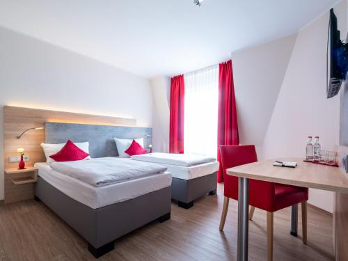 a bedroom with two beds and a desk and a table at Landhotel Fettehenne in Leverkusen