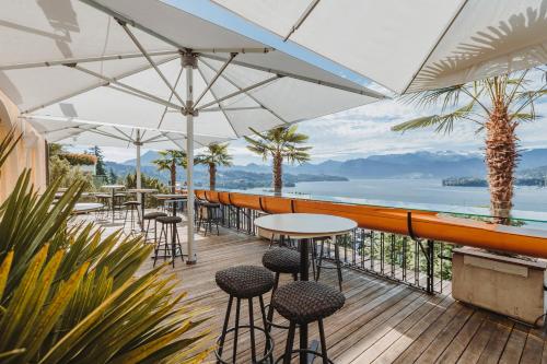 a patio with tables and chairs and a view of the water at Art Deco Hotel Montana Luzern in Luzern