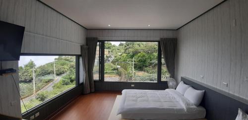 1 dormitorio con 2 ventanas grandes y 1 cama en Green incense Homestay, en Zhuqi