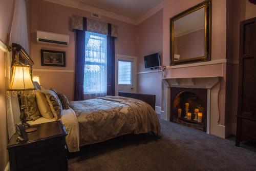 a bedroom with a bed with a fireplace and a mirror at Heytesbury House in Cobden