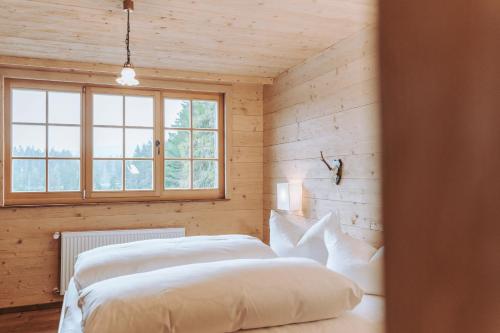 a bedroom with two white beds in a wooden wall at Hotel Am Fichtelsee in Fichtelberg