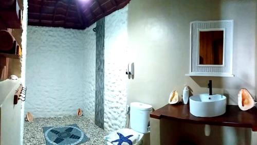 W łazience znajduje się toaleta, umywalka i lustro. w obiekcie Nini's Beach Bungalows w mieście Bira