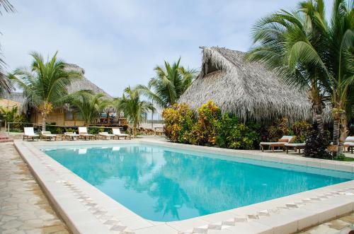 - une piscine en face d'un complexe avec des palmiers dans l'établissement Las Cabañas de Antica, à Vichayito