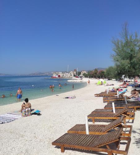 a beach with lounge chairs and people in the water at ISSA Holiday Home - 3 Min Walk to Beach in Kaštela