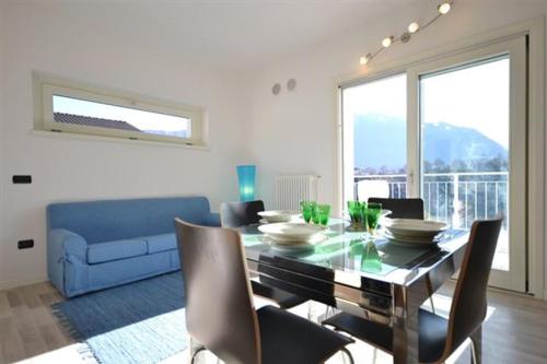 comedor con mesa y sofá azul en Gardenia Apartment Ossuccio, en Ossuccio