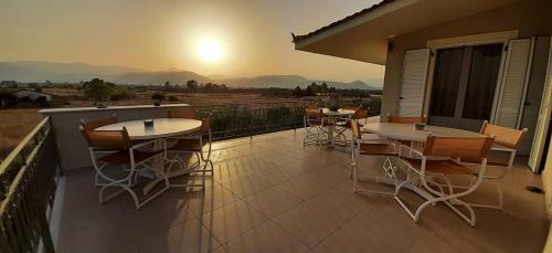 a patio with tables and chairs on a balcony at The Villa of the Winds in Néa Kíos