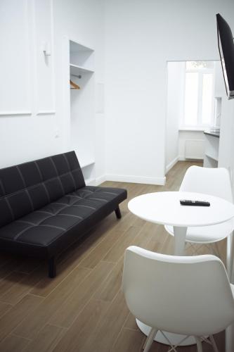 a living room with a black couch and a white table at Residence Odesskij Dvorik in Odesa