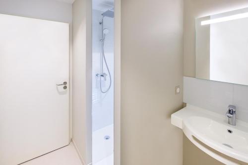 a white bathroom with a shower and a sink at The Originals City, Hôtel Acadine, Pont-Audemer in Pont-Audemer