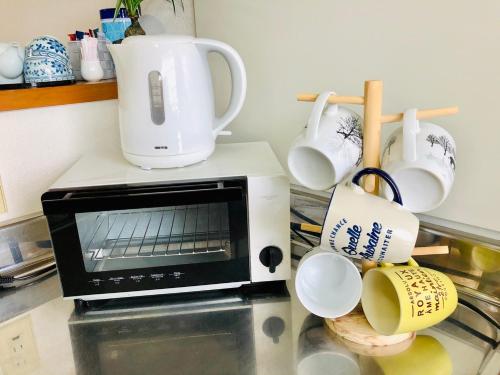 a microwave sitting on top of a counter with mugs at Nikko Dream House in Nikko