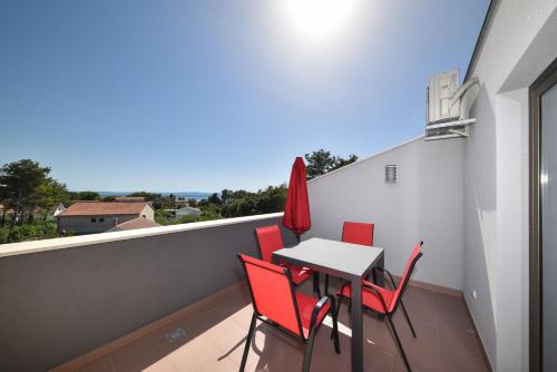 a balcony with a table and red chairs on it at APARTMANI PETRA in Vir