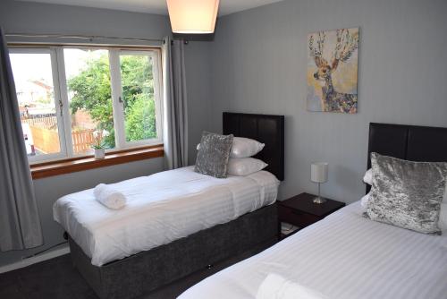 a bedroom with two beds and a window at Kelpies Serviced Apartments- Jamieson in Stenhousemuir