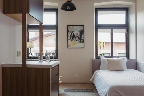 a bedroom with a bed and a sink and windows at Pod Jasną 28 in Częstochowa
