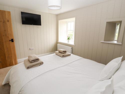 a bedroom with a large white bed with towels on it at Sgubor in Holyhead