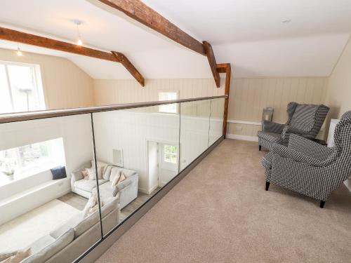 a living room with a glass railing and two chairs at Sgubor in Holyhead