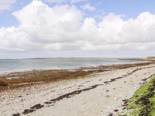 a gravel road leading to the ocean on a cloudy day at Sgubor in Holyhead