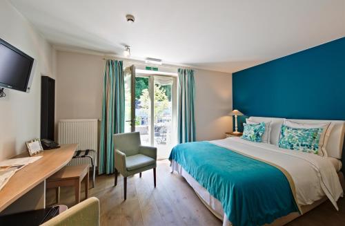 a bedroom with a blue wall and a bed and a desk at Hotel Saint-Amour in Durbuy