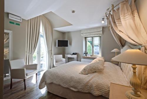 a bedroom with a bed and a chair and a television at Hotel Saint-Amour in Durbuy