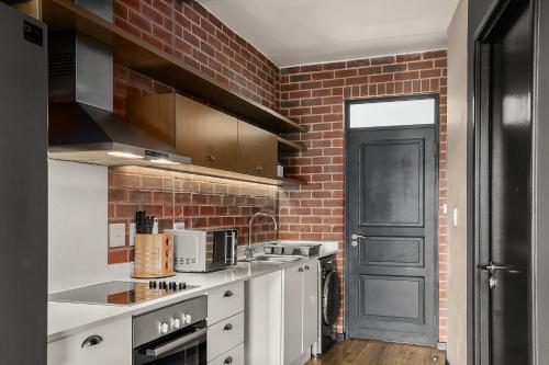 a kitchen with white counters and a brick wall at Easy Stay - The Vantage Rosebank in Johannesburg