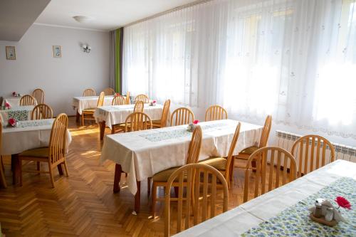 a dining room with white tables and wooden chairs at Zacisze Natura Tour in Spała