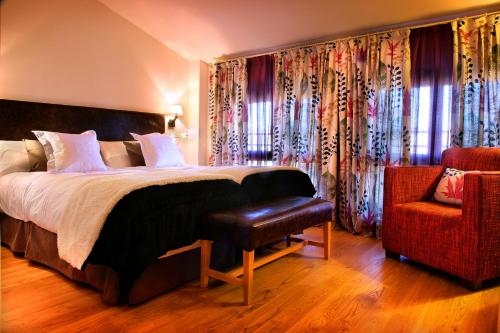 a bedroom with a bed and a chair and curtains at Hostería de Guara in Bierge