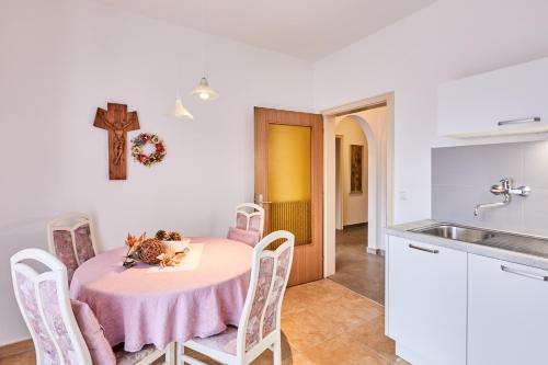uma cozinha com uma mesa e uma cruz na parede em Apartmenthaus Haringer em Novacella