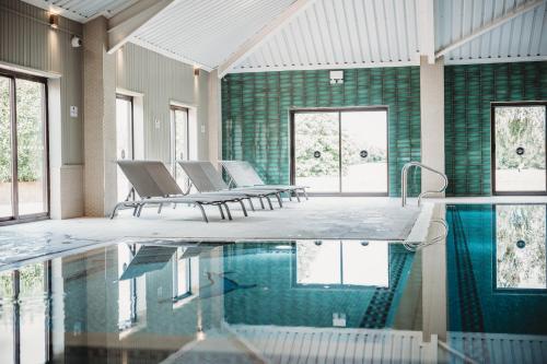 um quarto com uma piscina com cadeiras e janelas em The Essex Golf & Country Club Hotel em Coggeshall