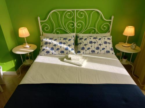 1 cama con cabecero verde y 2 mesas con lámparas en B&B Stella Scugnizza en Nápoles
