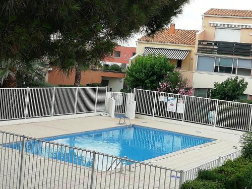 une piscine avec une clôture blanche à côté d'un bâtiment dans l'établissement Résidence les Estivales, au Cap d'Agde