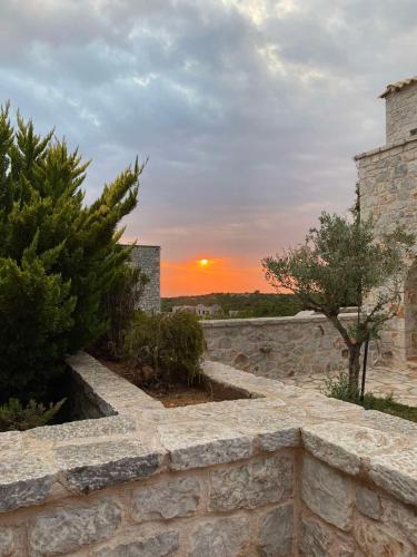 a stone wall with a sunset in the background at Achelatis Traditional Guest Houses in Areopolis