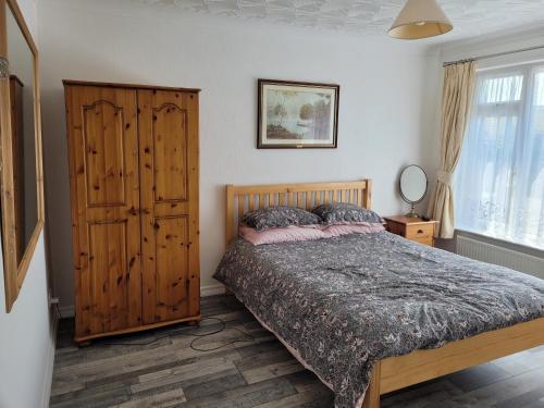1 dormitorio con 1 cama y armario de madera en Sandy Retreat en Worle