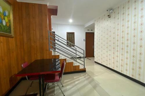 a dining room with a table and a staircase at RedDoorz Plus @ Rawamangun in Jakarta