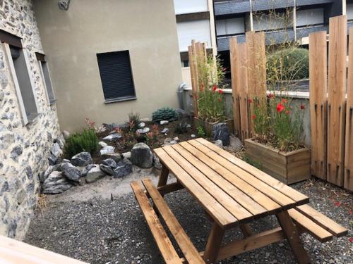 a wooden picnic table in a garden with a fence at La Grange des Riders in Saint-Lary-Soulan
