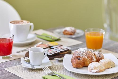 a table topped with plates of pastries and cups of coffee at Sweet Central Hotel in Caserta