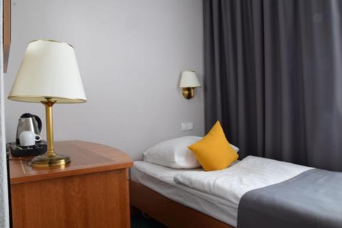 a hotel room with a bed and a lamp on a table at Hotel Festival in Opole
