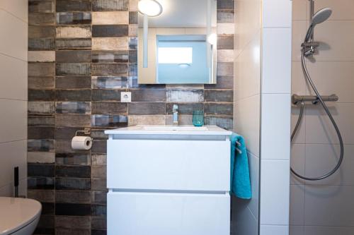 La salle de bains est pourvue d'un lavabo blanc et d'un miroir. dans l'établissement Vakantiewoning B & Bernard, à Domburg