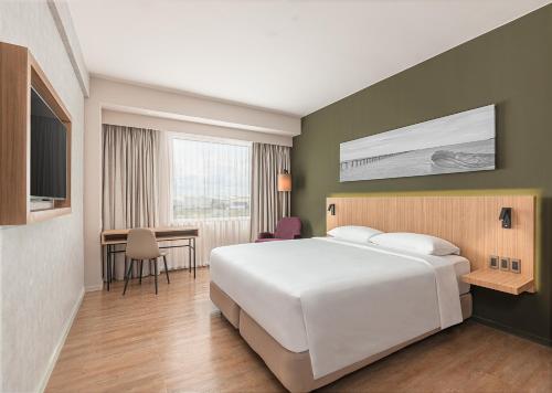 a bedroom with a large white bed and a desk at Park Inn By Radisson Bacolod in Bacolod